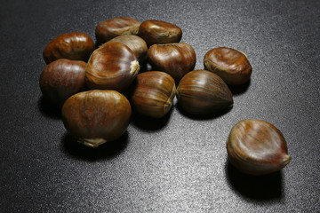 heap of chestnuts on black shiny background