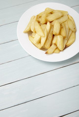 A bowl of French fries on a blue wooden dining table background, with empty space below