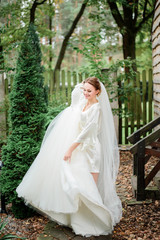 Bride whirls with her wedding dress on porch covered with fallen leaves