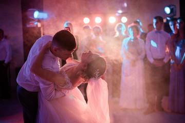 Groom bends bride over while they dance in the smoke at the first time
