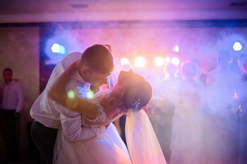 Groom bends bride over while they dance in the smoke at the first time