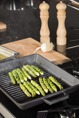 a handful of green asparagus cooking and steaming on grill plate
