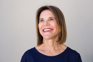 elderly woman laughing against gray background