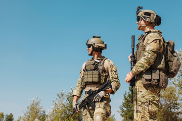 US Army Rangers with weapons in the desert. Plate carriers, eyewear goggles and combat helmets are protecting them