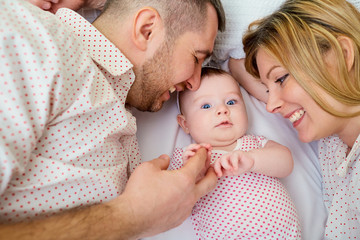 Mother and father with smiling baby lying. Happy family.