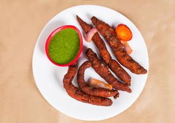 Chicken fingers - a spicy Indian dish served with green coriander chutney clicked on brown background available with clipping path