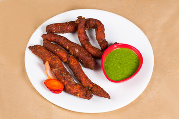 Chicken fingers - a spicy Indian dish served with green coriander chutney clicked on brown background available with clipping path