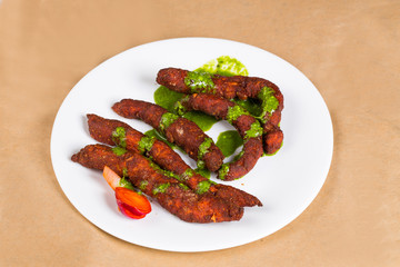 Chicken fingers - a spicy Indian dish served with green coriander chutney clicked on brown background available with clipping path