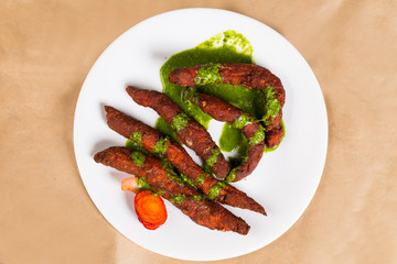 Chicken fingers - a spicy Indian dish served with green coriander chutney clicked on brown background available with clipping path