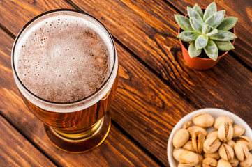 glass of dark cold frothy beer, nuts old wooden table