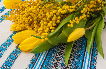 Mimosa and tulips on an embroidered towel (products of mass production)