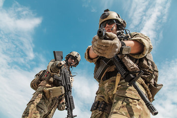 Fototapeta premium US Army Rangers pointing weapons to the camera detaining person. Low angle view