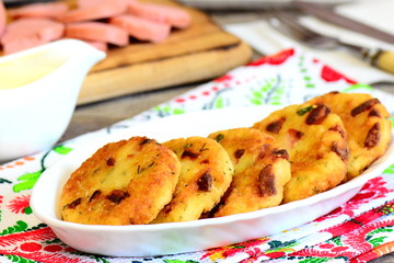 Home couscous cakes with sausage and herbs on a plate and on textile napkin. Tasty fried grits cakes for breakfast. Closeup