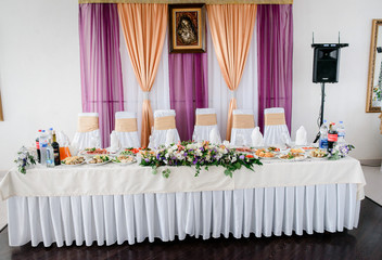 Icon hangs over long dinner table decorated with flowers for wedding couple