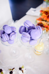 Fototapeta na wymiar Bowls with violet macaroons stand on white table