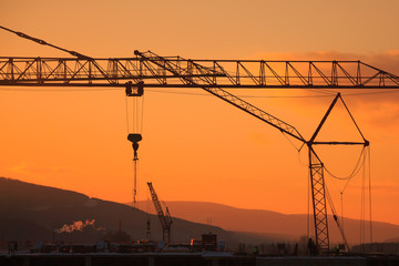 Construction crane and skyscraper at sunset