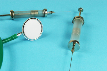 Stethoscope and syringe on blue background.