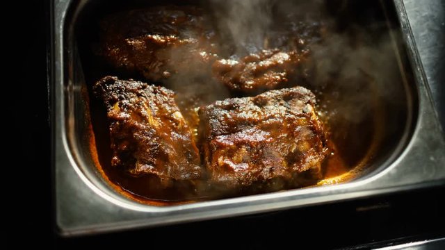 Hot meat dishes with pork ribs with gravy boiling sauce at restaurant kitchen