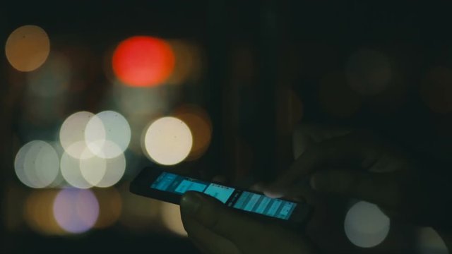 Hand holding a smartphone and writing mesage on nigth city background