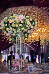 Gorgeous centrepiece made of pastel orange rose stands in the middle of dinner table