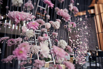 Pink chrysanthemums hang on threads from the ceiling in dinner hall