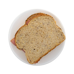 Top view of an applewood smoked ham sandwich on a plate isolated on a white background.