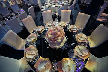 Look from above at round dinner table with mirror cover decorated with pink flowers