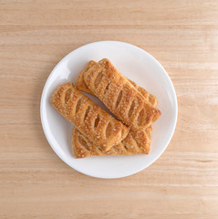 Top view of apple fruit tarts on a white plate atop a wood table.
