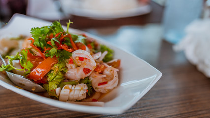 Delicious spicy fresh seafood salad decorate with a vegetables on dish.