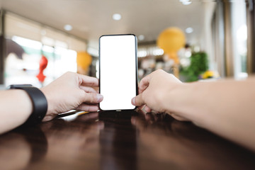 Close up hands holding cell telephone with blank copy space screen for your advertising text message or promotional content, in coffee shop, in selective focus.