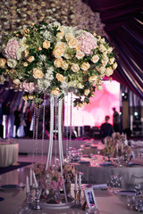 Large centrepiece made of bunch of roses on tall vase with chains