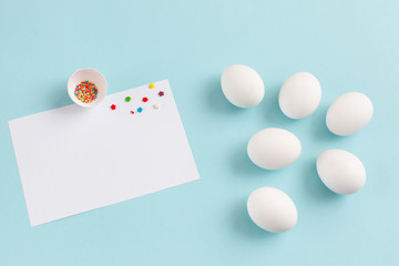 Easter decoration white eggs and broken egg with colored sugar ingredients on a light blue background, white sheet of text, horizontal image