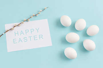 Easter decoration, white eggs and willow twig on a light blue background, white sheet of text, horizontal image