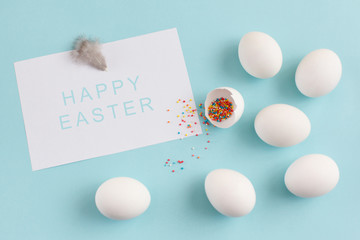 Easter decoration white eggs and broken egg with colored sugar ingredients on a light blue background, white sheet of text, horizontal image