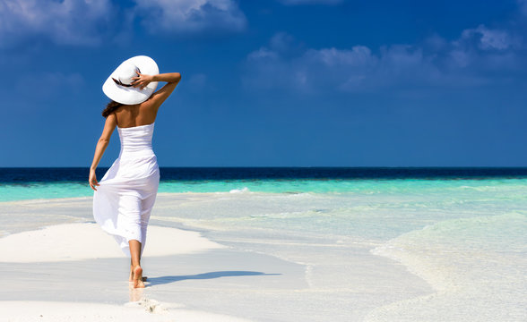 Attraktive Frau in wei&szlig;em Kleid l&auml;uft auf einer Sandbank in den Tropen