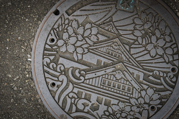OSAKA, JAPAN - OCTOBER 20, 2016: Manhole cover in Osaka, Japan. The Osaka castle engraved on to a manhole cover as a symbol of an important city's landmark.