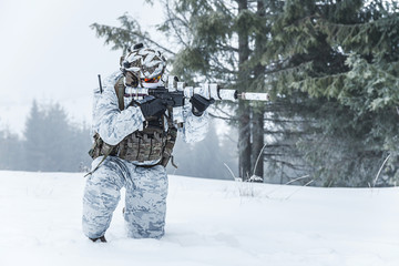 Winter arctic mountains warfare. Action in cold conditions. Trooper with weapons in forest...