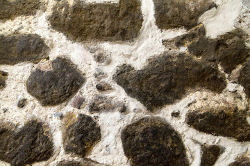 Textured stone walls built of large rough stones held together by dark lumps of white cement limestone