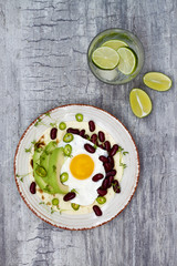 Mexican huevos rancheros tacos. Breakfast tostadas with black beans, avocado, fried egg, microgreens, sriracha ketchup.Top view, flat lay, copy space