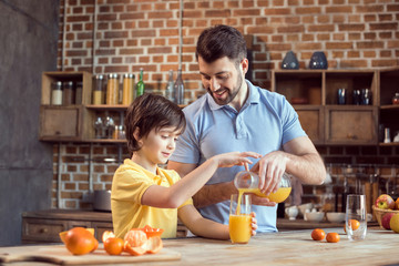 Happy father and son pouring fresh juice in glass