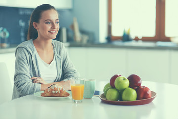 Young woman with orange juice and tablet in kitchen