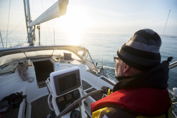 Man Steering Yacht At Helm During Sunset