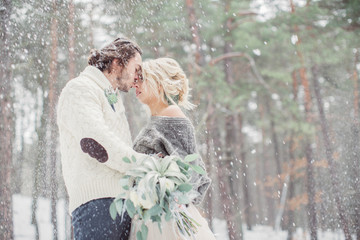 Beautiful romantic couple kissing in the winter forest outside