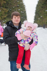 Dad and daughter on a walk in the park in winter. Dad holding a baby in her arms