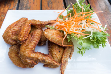 Chichen wing fried with salad in white dish on wooden table with copyspace ,flat lay