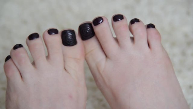 Female feet with a dark paint on nails