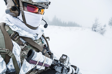 Winter arctic mountains warfare. Action in cold conditions. Trooper with weapons in forest...