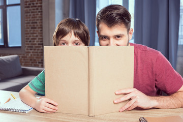 father and son looking out of book at home