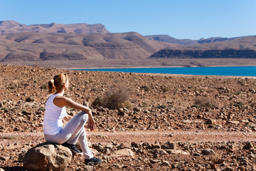 Fototapeta na wymiar femme assise vers un lac au milieu de montagnes et de rochers