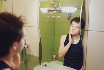 young man looks at himself in the mirror